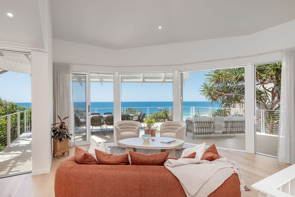 Living room with TV, air conditioning, balcony access and coastal outdoor views.