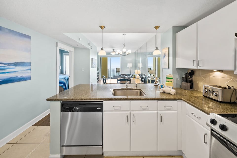 Your fully equipped kitchen features granite countertops, stainless steel appliances, and an open layout perfect for preparing meals with ocean-inspired décor.