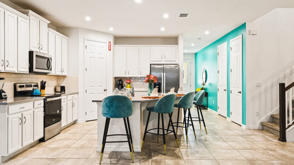 Modern kitchen with bright accents, island seating, and stainless steel appliances.