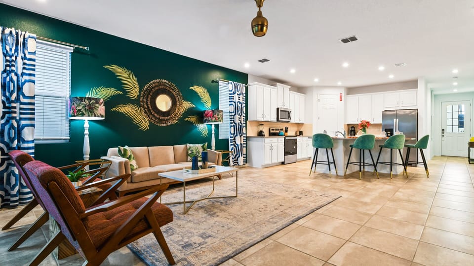 Spacious open-concept living with tropical decor, modern kitchen, and cozy seating.