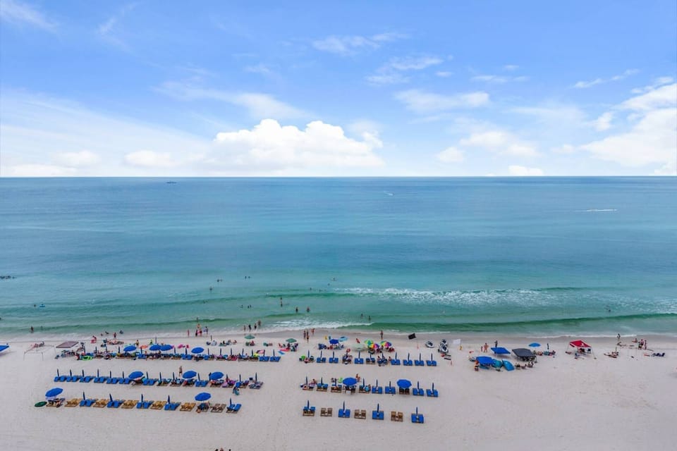 Relax on the sandy beach with organized lounge chairs and umbrellas by the calm ocean.