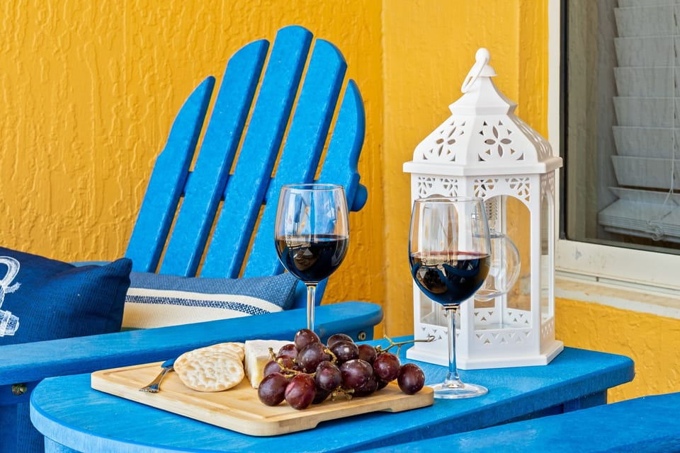 Relax with wine and snacks on the blue Adirondack chair against a vibrant yellow wall.