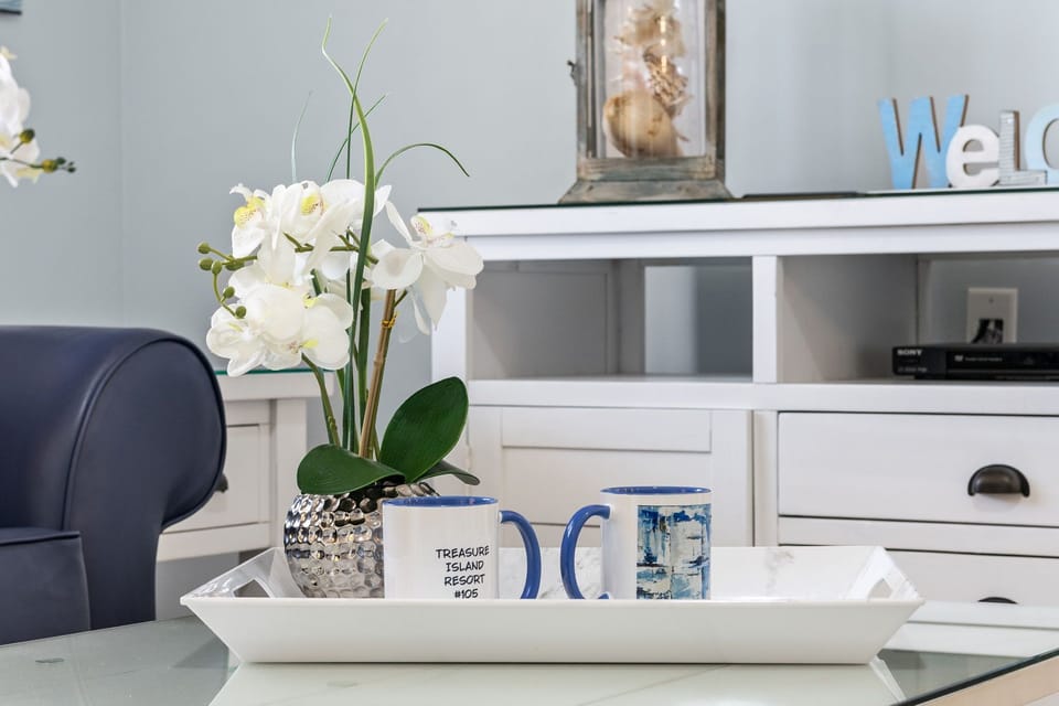 A modern tray with decorative orchids and coffee mugs adds a welcoming touch to the living area.