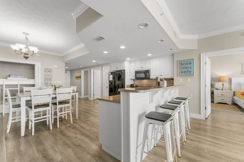 Open kitchen and dining area with modern white cabinetry and bar seating.