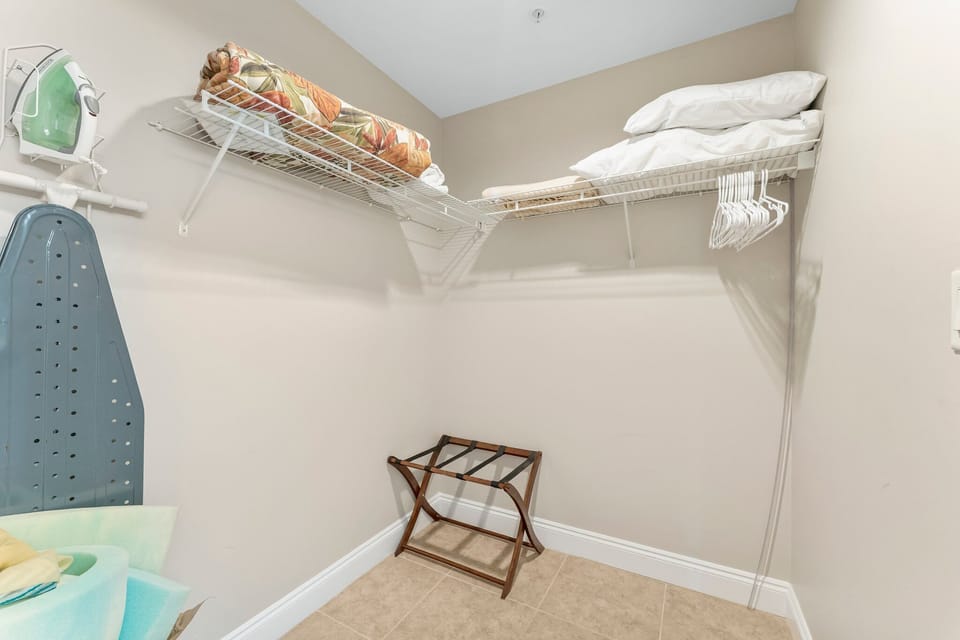 Closet space with shelving and an ironing board for guest convenience