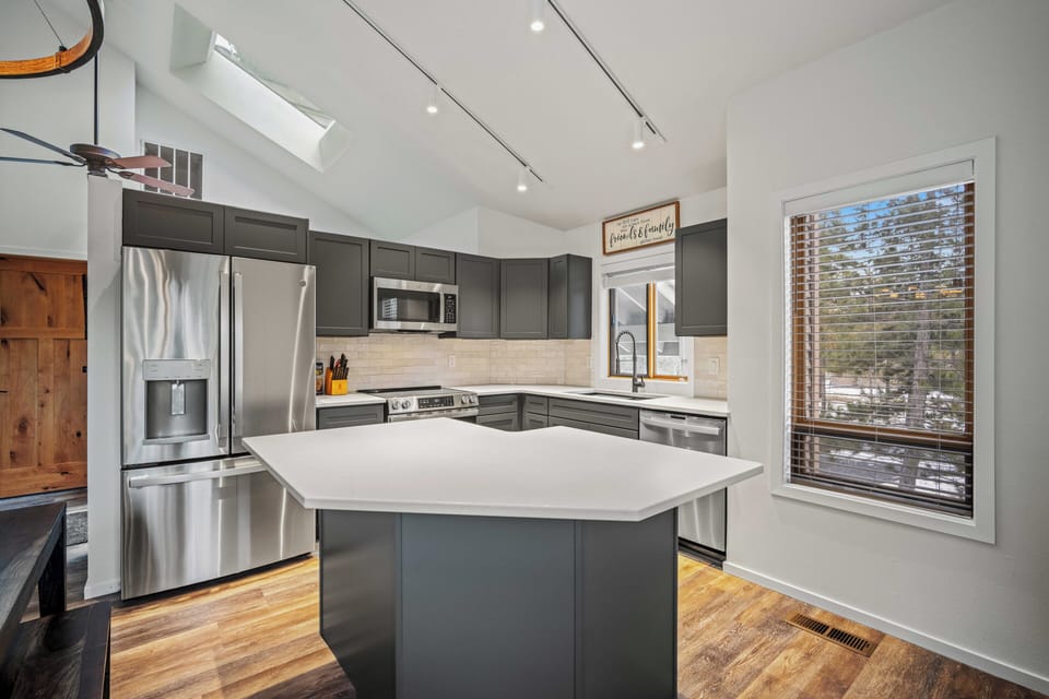 Step into your gourmet kitchen with sleek gray cabinetry, stainless steel appliances, and a spacious island perfect for cooking and gathering.