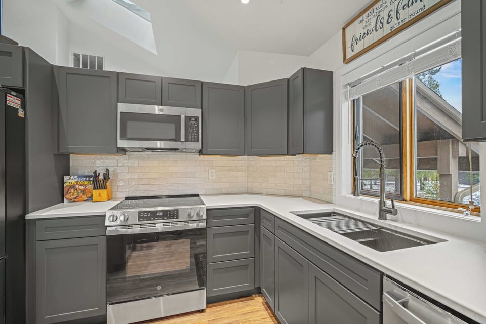 Your fully equipped kitchen features modern gray cabinets, stainless steel appliances, and bright natural light for preparing memorable meals during your stay.