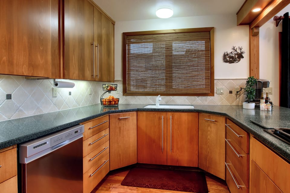 Bright corner kitchen with sink, dishwasher, and storage.