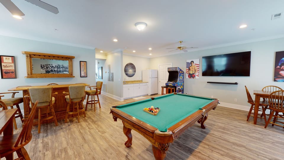 Fun-filled room with pool table, arcade games, and cozy bar seating.