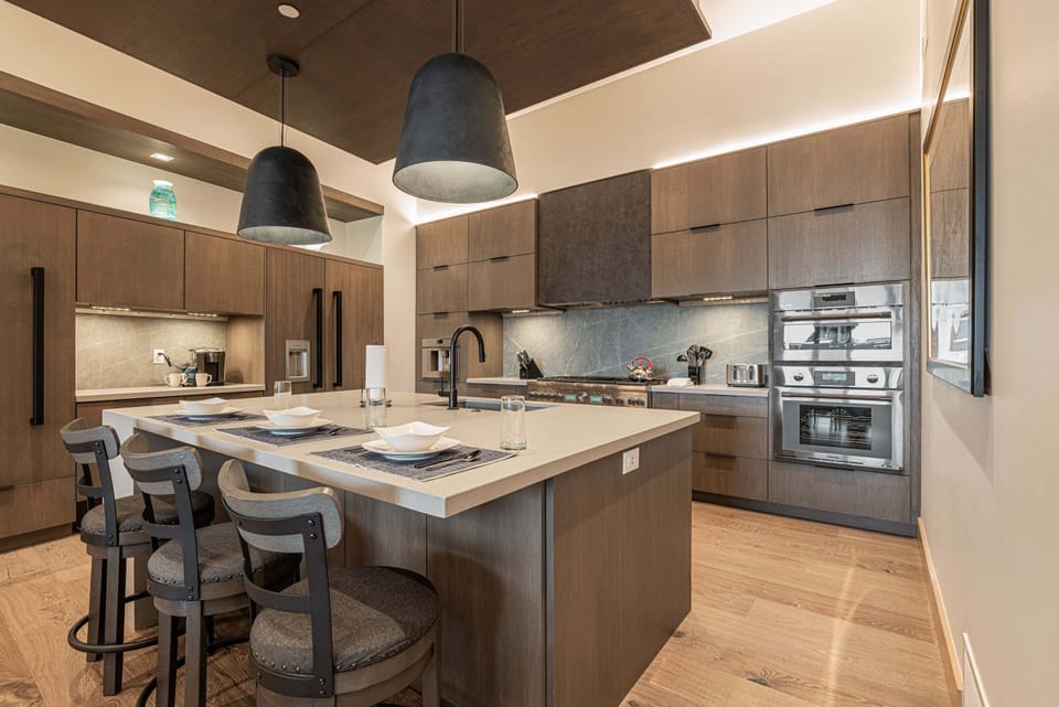 Open and fully equipped kitchen with gas range, stone countertops, and island seating