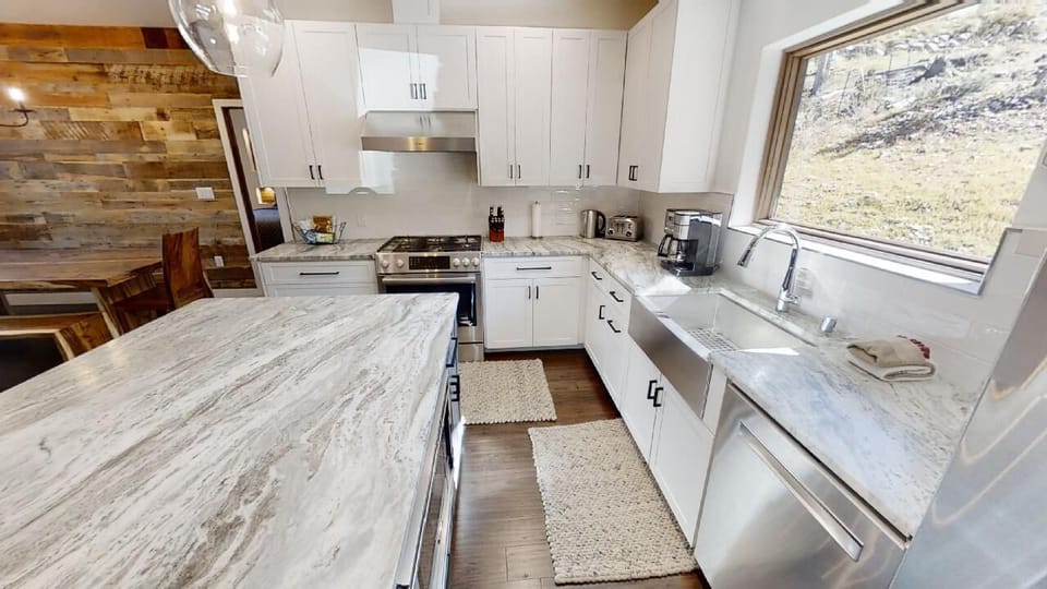 Step into your fully equipped kitchen where sleek marble countertops and modern appliances make cooking a pleasure, all while scenic mountain views inspire your culinary creativity.