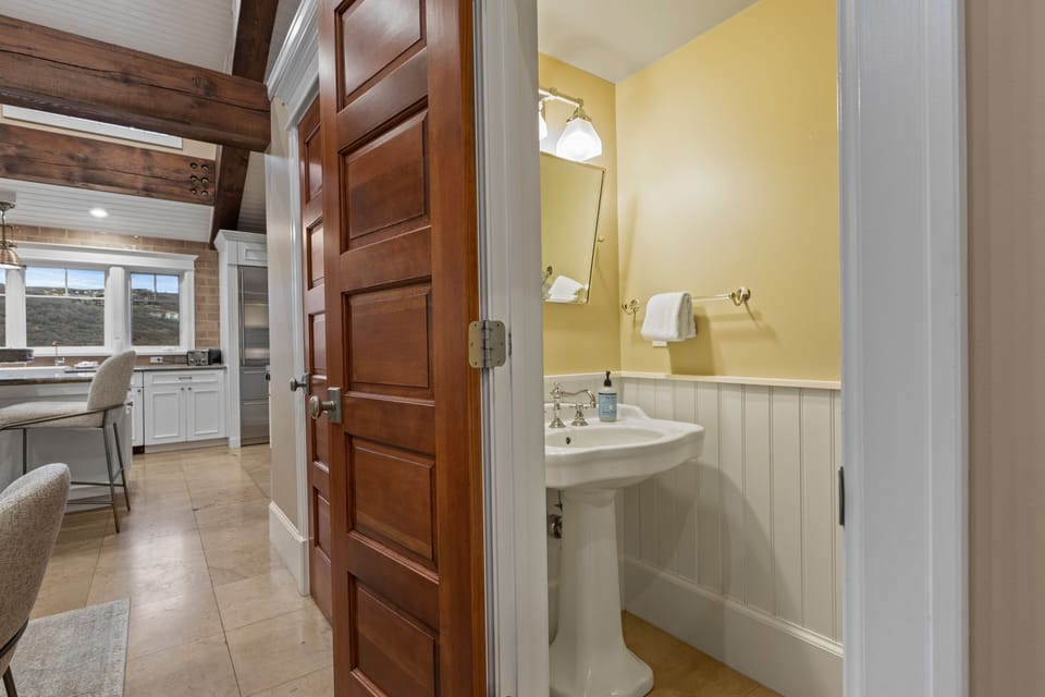 Enjoy the vintage charm of our powder room, featuring custom woodwork, a classic pedestal sink, and easy access from the main living area.