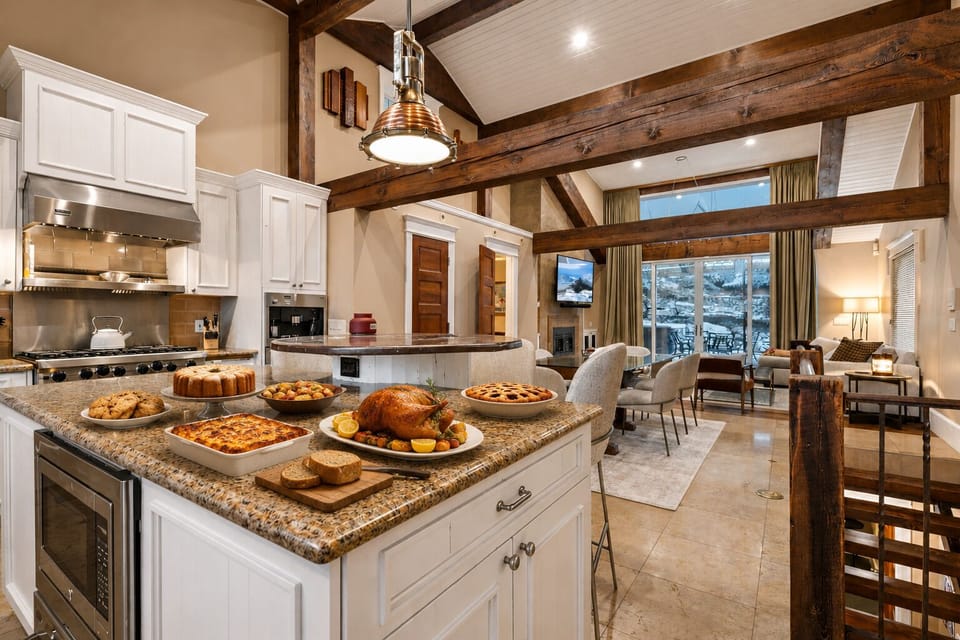 A stunning open-concept space where your group can gather around the gourmet kitchen island, sharing meals beneath rustic wood beams, then relax in the cozy living area with mountain views.