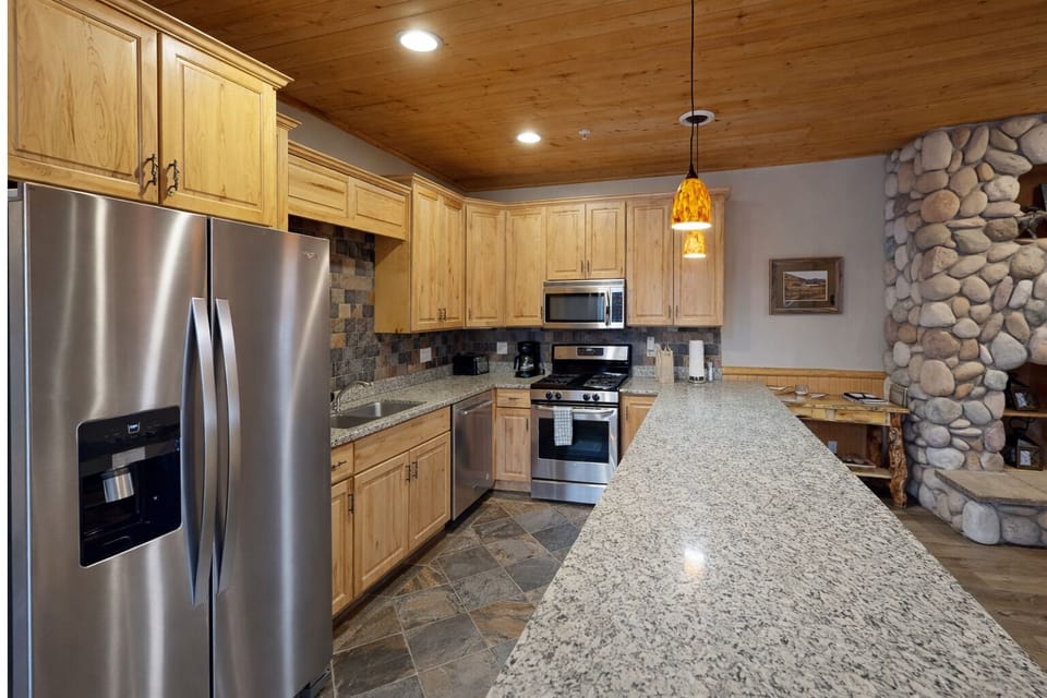 Your fully equipped kitchen features granite countertops, stainless steel appliances, and warm wood cabinetry, perfect for preparing memorable meals together.