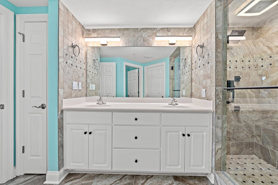 Modern bathroom featuring a double vanity and tiled walk-in shower.
