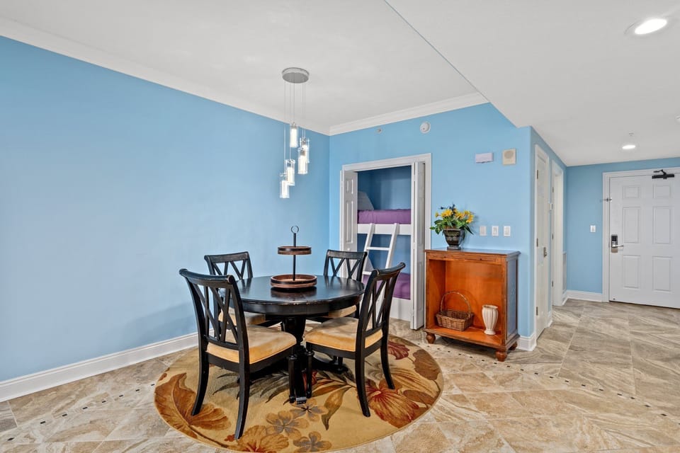 Dining area with a round table and modern pendant lighting against a blue wall