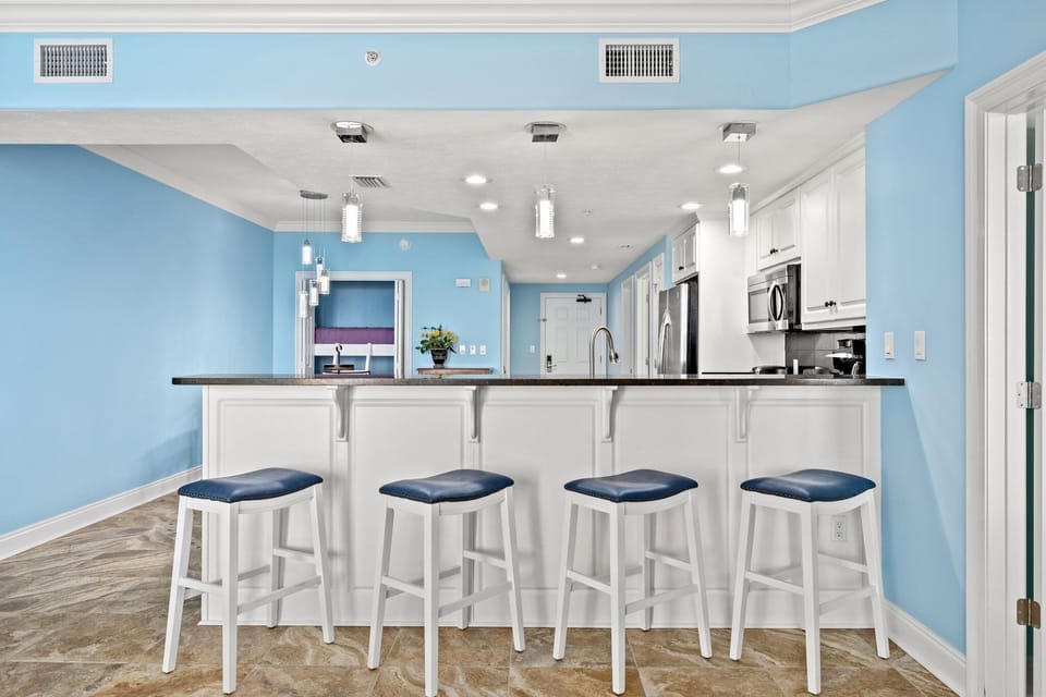 Modern kitchen with a blue accent wall and a breakfast bar with four stools.