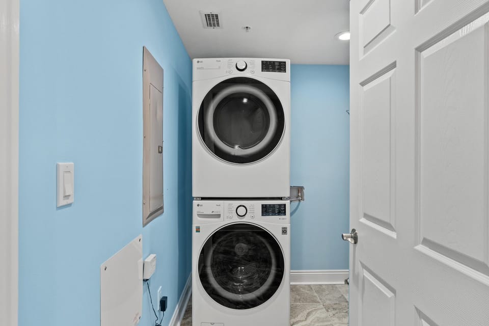 Stacked washer and dryer in a compact laundry room with light blue walls.