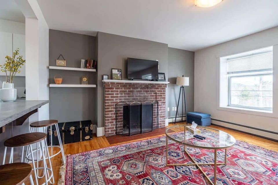 Bright and inviting  living room with abundant natural light. Relax on the cozy sofa by the charming fireplace—perfect for unwinding after a day of exploring. 