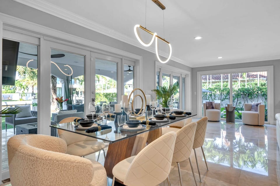 A dining table for six sets seamlessly in front of floor to ceiling windows with views of the waterway and immaculate back yard.
