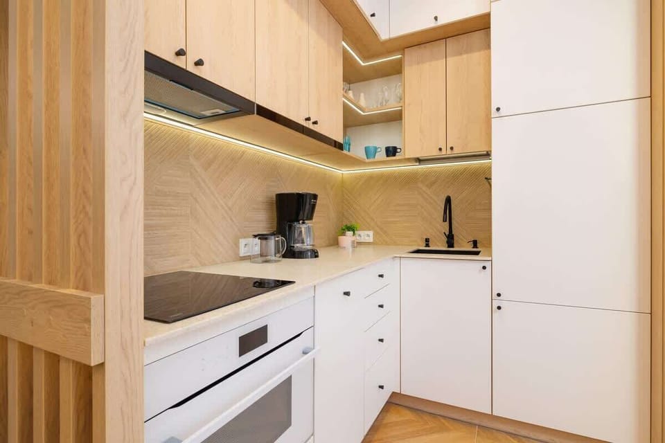 A modern kitchen with white cabinets, wooden countertops, and sleek appliances, maintaining a minimalist and elegant design.
