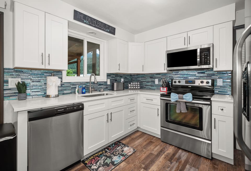Bright modern kitchen with stainless appliances and stylish blue tile accents