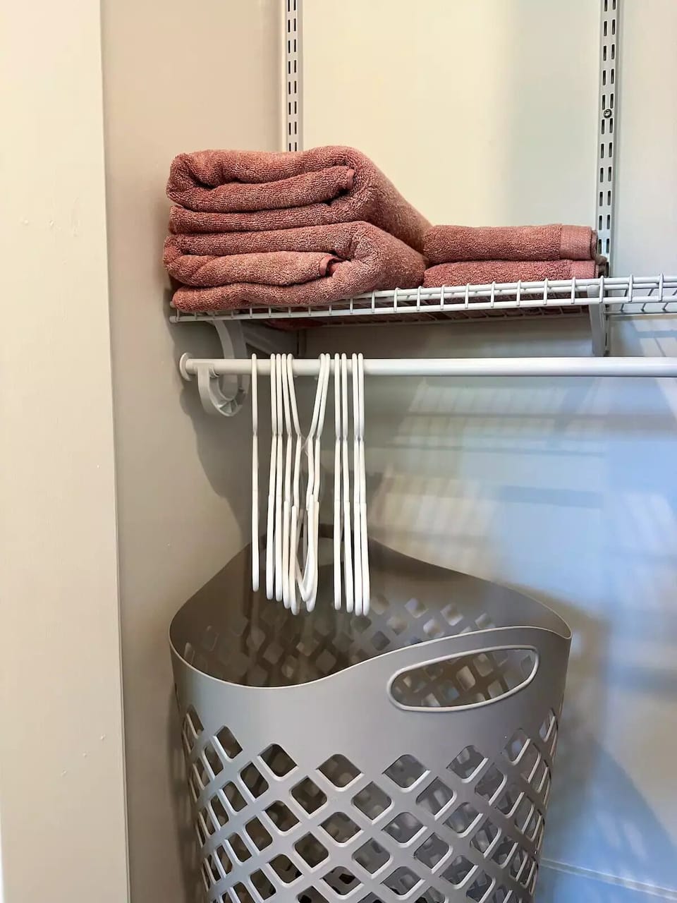 Custom closet in bedroom 1 with towels, hangers and a laundry basket