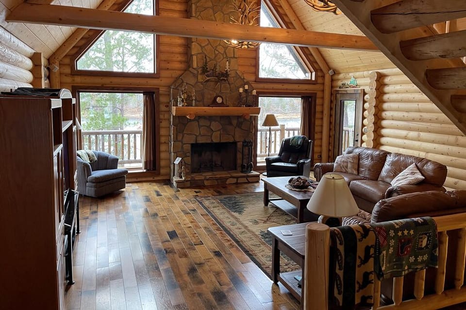 Large vaulted log great room with fireplace, antler chandeliers and lake views.