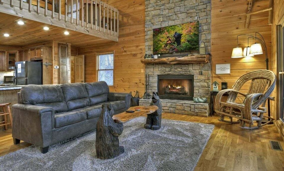 Cozy living room with a stone fireplace, bear-themed decor, and rustic charm.