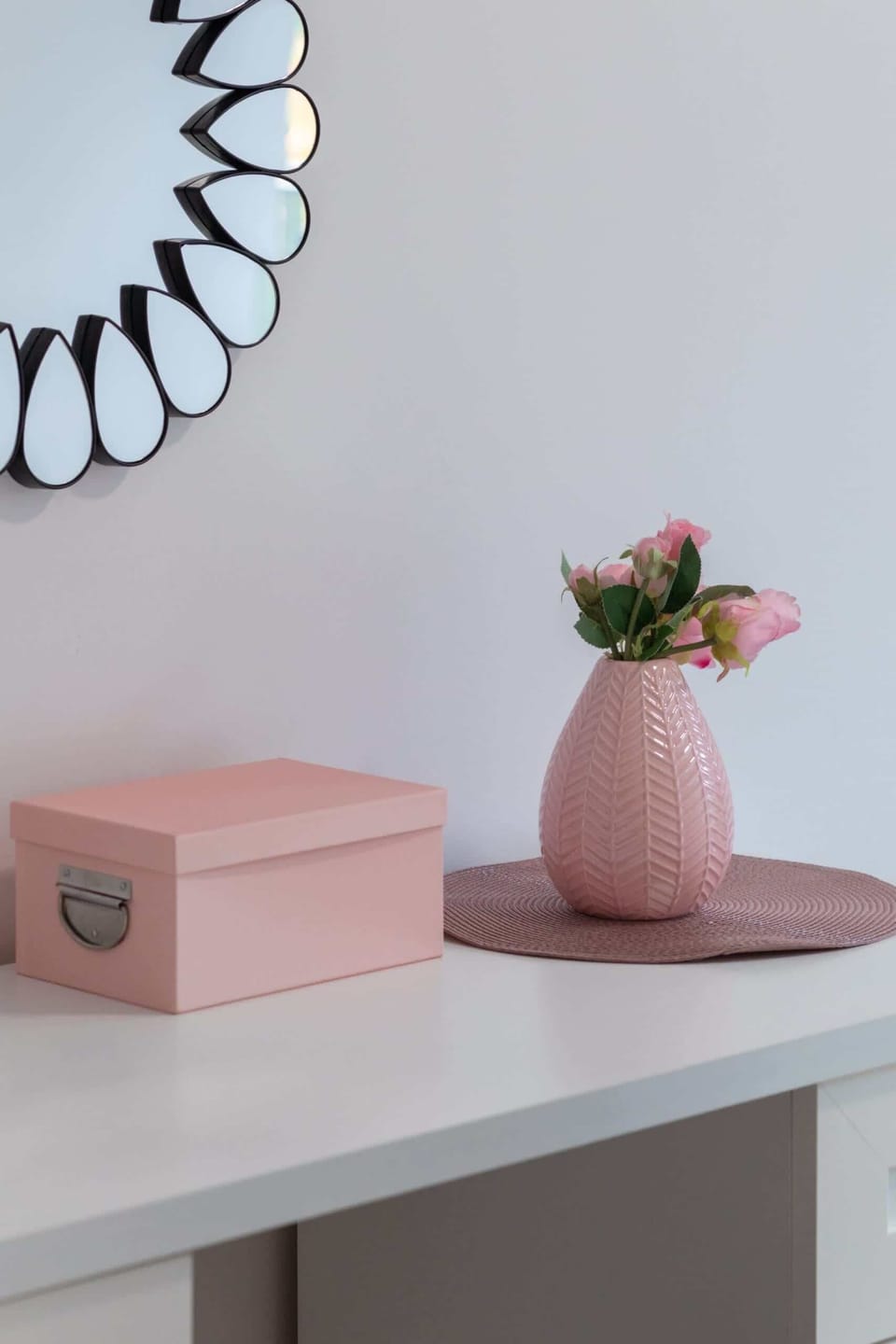 A decorative setup featuring a pink vase and box on a minimalist shelf, adding charm to the interior.
