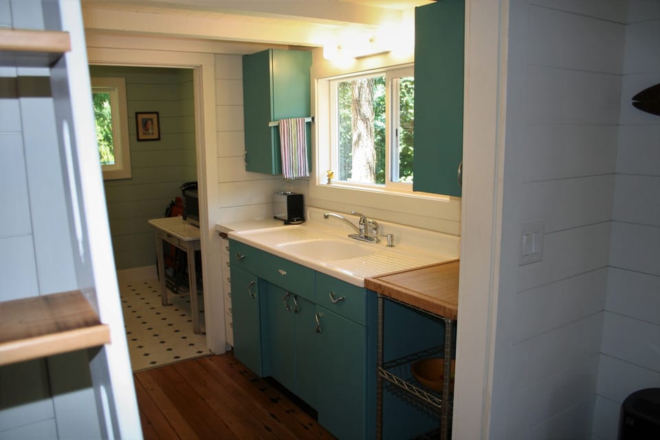 Vintage metal cabinets and porcelain sink in the kitchen.  View of river/dock