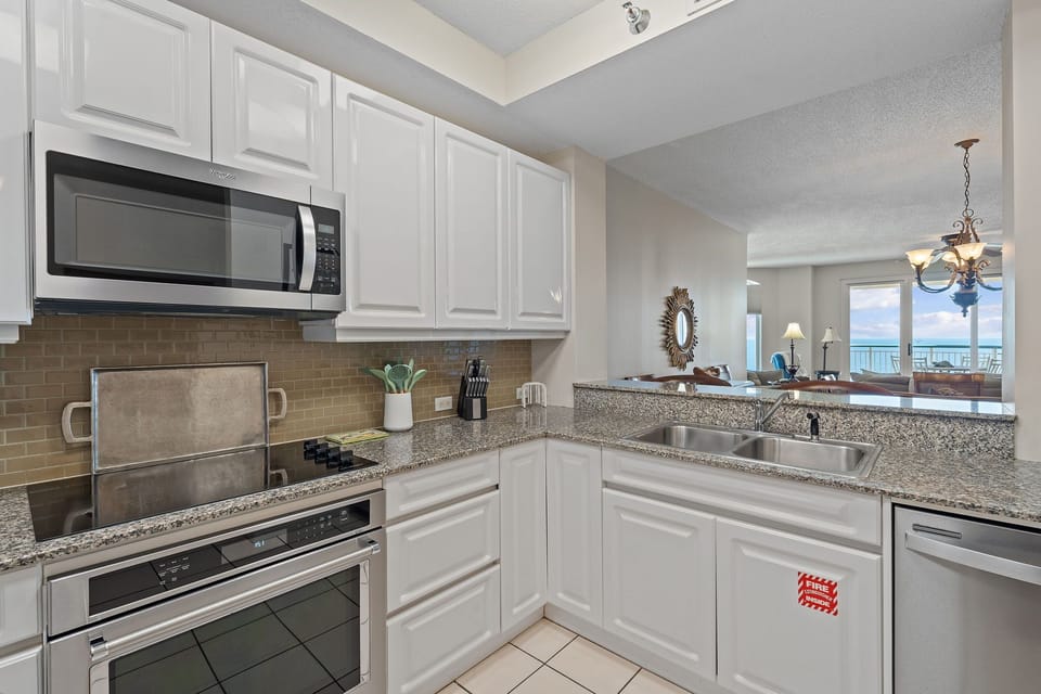 Beach Colony T15B- Your fully equipped kitchen awaits with everything you need to prepare meals—granite counters, stainless appliances, and an open view into the living area where that sparkling ocean view beckons.