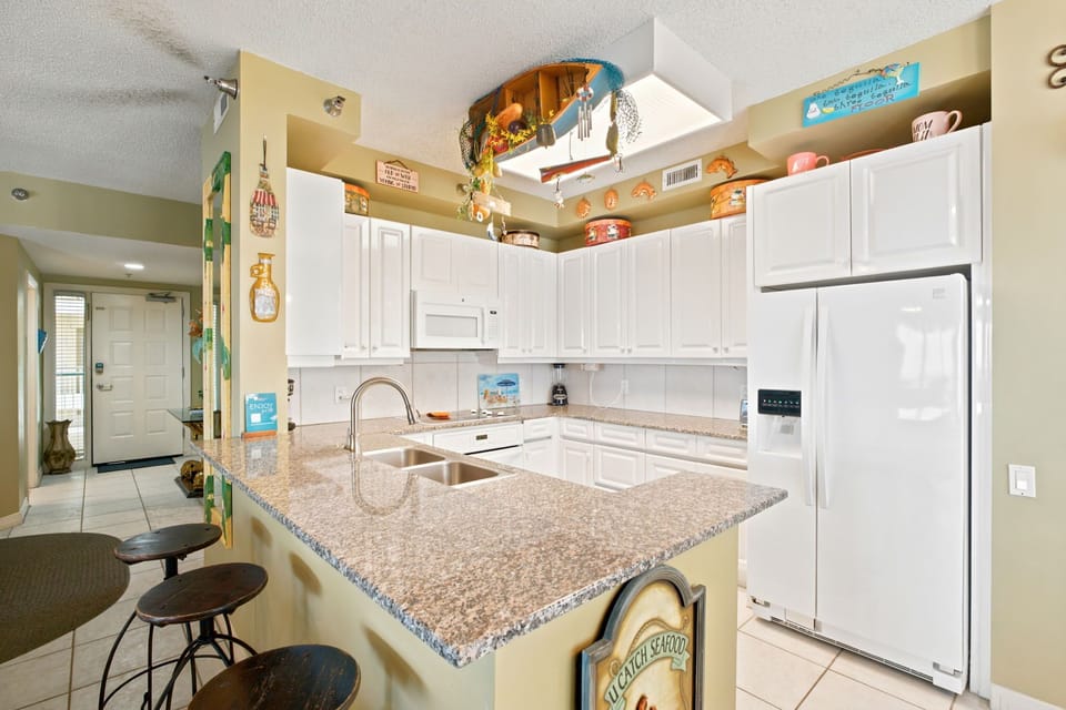 Beach Colony W13A- You'll love preparing meals in this bright, fully-equipped kitchen with granite countertops, modern appliances, and charming beach-themed touches that make it feel like home.