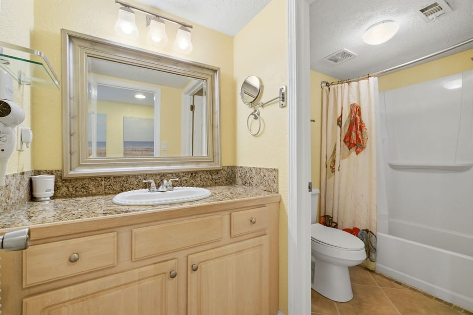 Ocean Breeze E601- Bathroom offers a granite-topped vanity, bright lighting, and a full tub-shower combo—perfect for unwinding after a day at the beach.