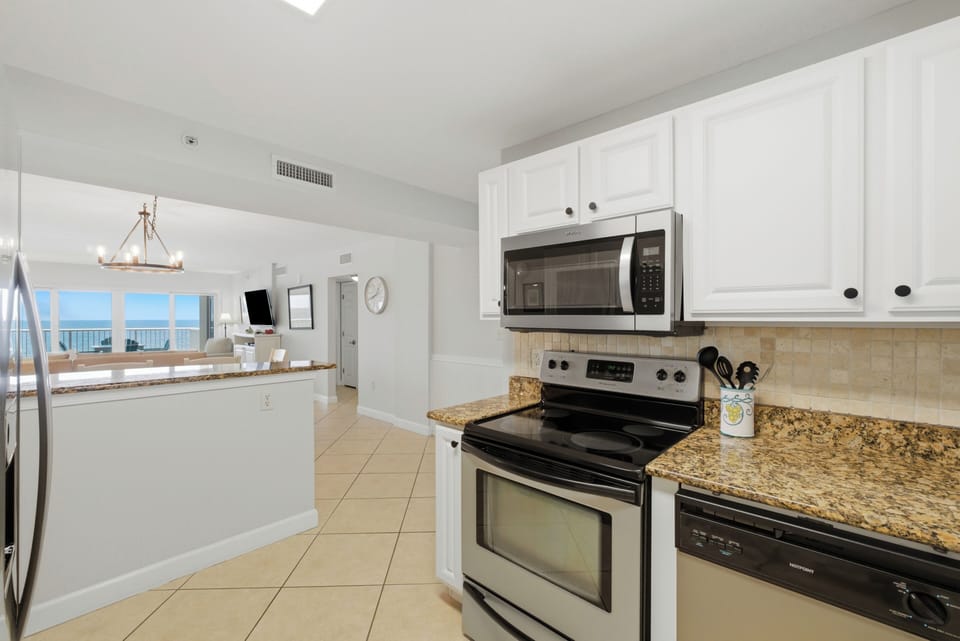 Sandy Key 318- Your kitchen features full-size appliances, granite counters, and crisp white cabinetry—all with stunning ocean views framing the open living space beyond.