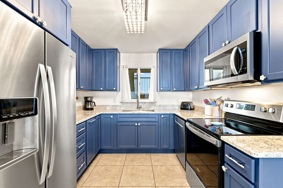 Sandy Key 411- Your fully equipped kitchen features stylish blue cabinetry, granite countertops, and stainless steel appliances—perfect for preparing meals at your own pace during your stay.