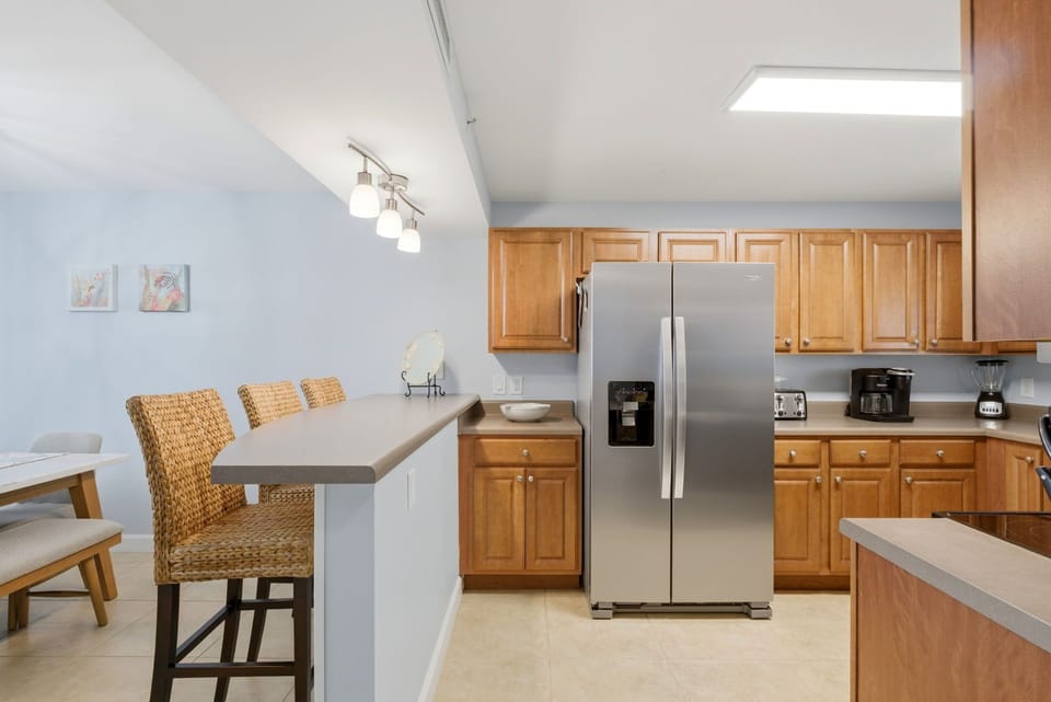 Sandy Key 637- Gather with loved ones in your fully equipped kitchen featuring stainless steel appliances, warm wood cabinetry, and an inviting breakfast bar perfect for casual meals.
