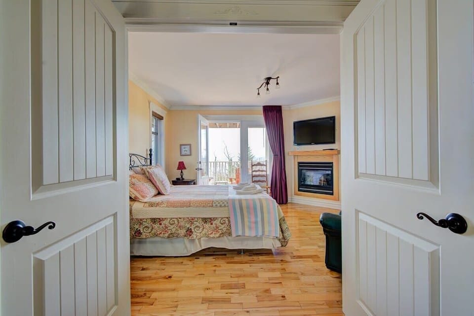 Chambre des maîtres avec lit Queen et foyer au gaz avec salle de bain privée et balcon
