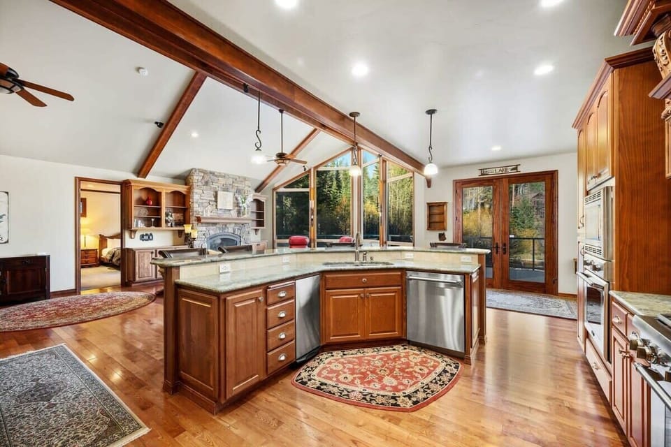 You'll love creating culinary masterpieces in this stunning open kitchen, where rich wood cabinetry and soaring beams frame beautiful forest views.