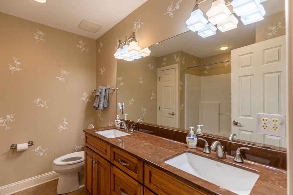 Two sinks, warm wood cabinetry, and delicate floral wallpaper make mornings feel a little more graceful at Moonlight Manor.
