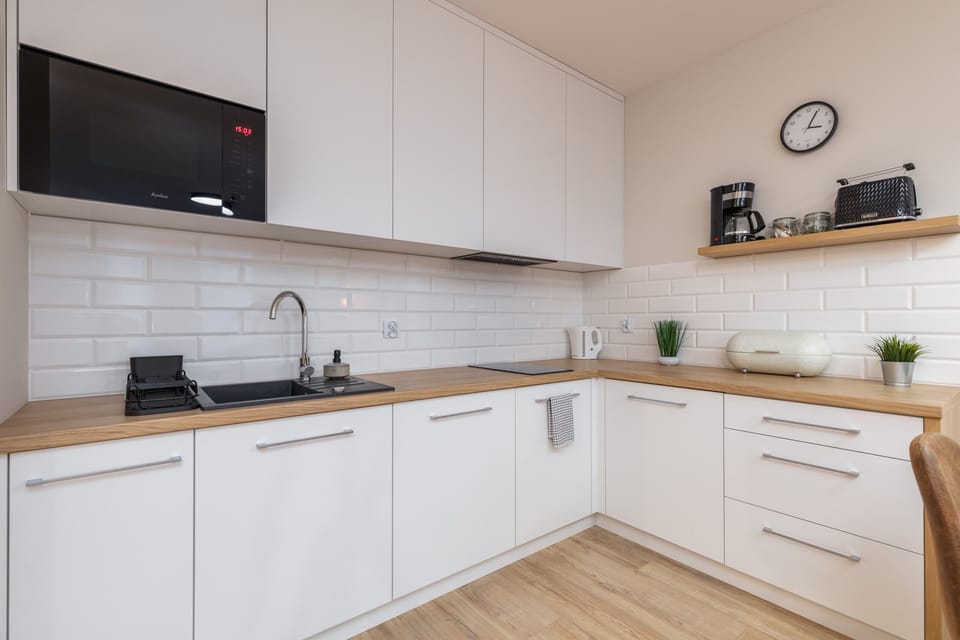 A modern kitchen with sleek white cabinetry, an induction cooktop, and all essential appliances.