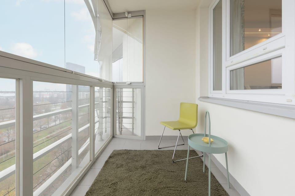 A cozy enclosed balcony with seating, ideal for relaxing with a view of the surroundings.
