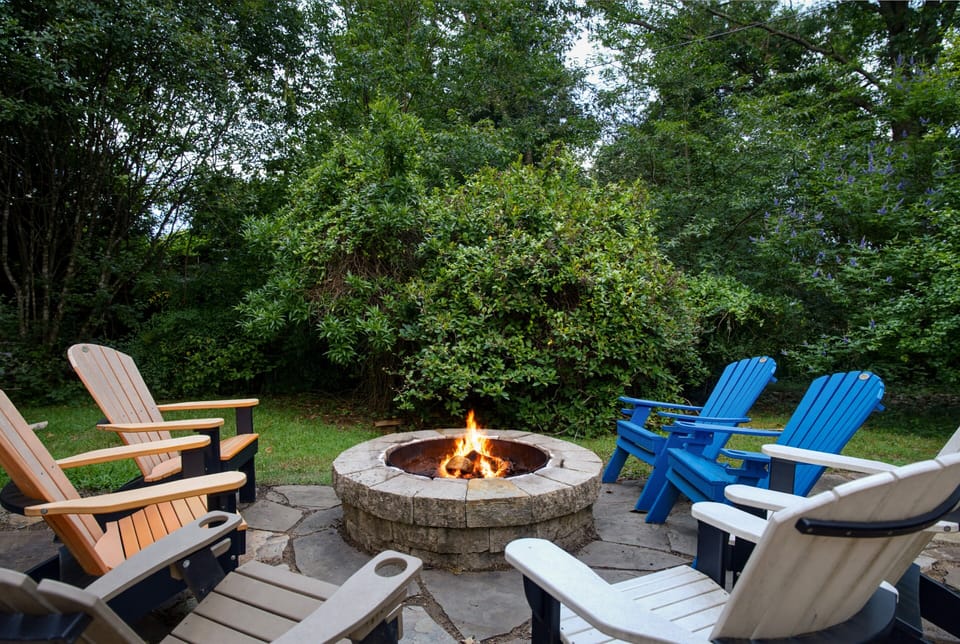 Private backyard fire pit with Adirondack seating in a lush, wooded setting