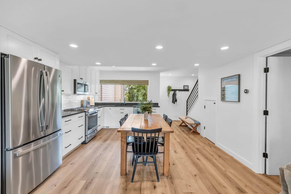 The kitchen and dining area is a dazzling space with a modern look featuring white cabinets, stainless steel appliances, and a beautiful wooden dining table with seating for 6.