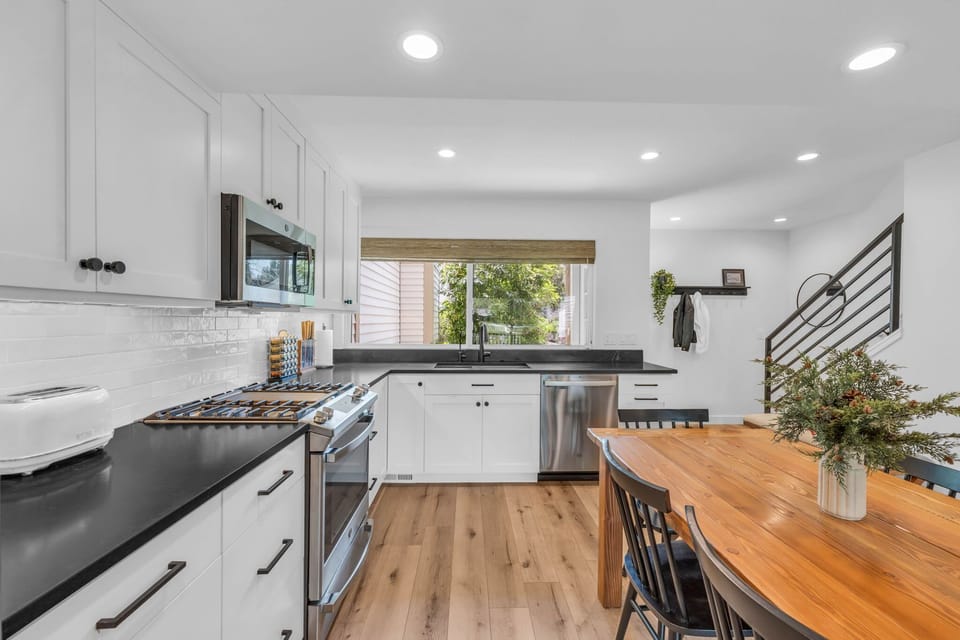 The kitchen and dining area is a dazzling space with a modern look featuring white cabinets, stainless steel appliances, and a beautiful wooden dining table with seating for 6.