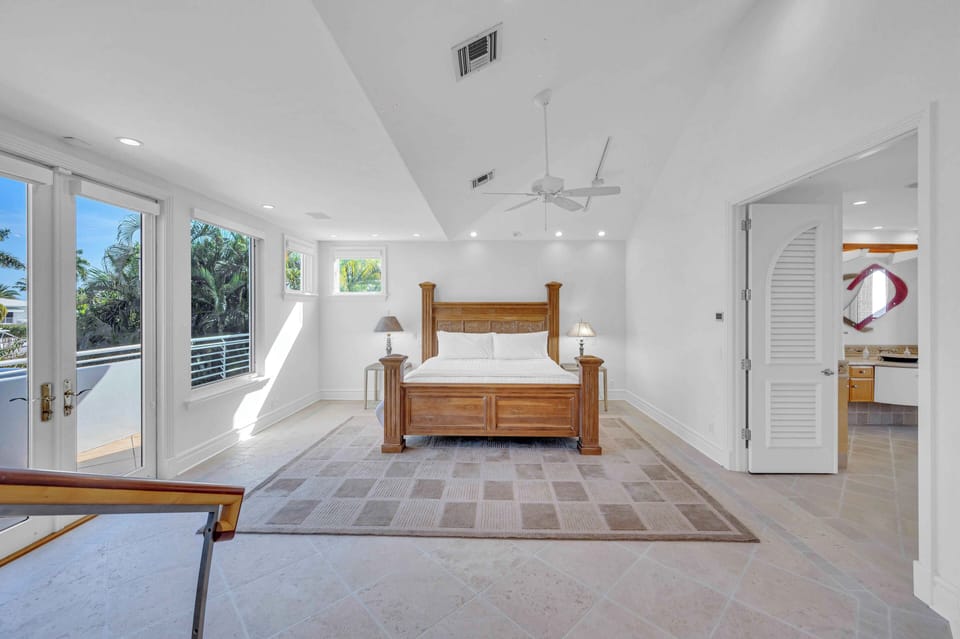 The primary bedroom features a King bed, smart tv, office area, a large walk in closet, ensuite bathroom and balcony access overlooking the backyard.