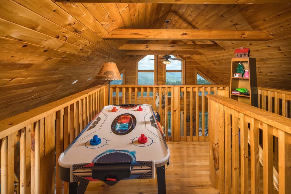Loft game area with an air hockey table and cozy cabin-style woodwork