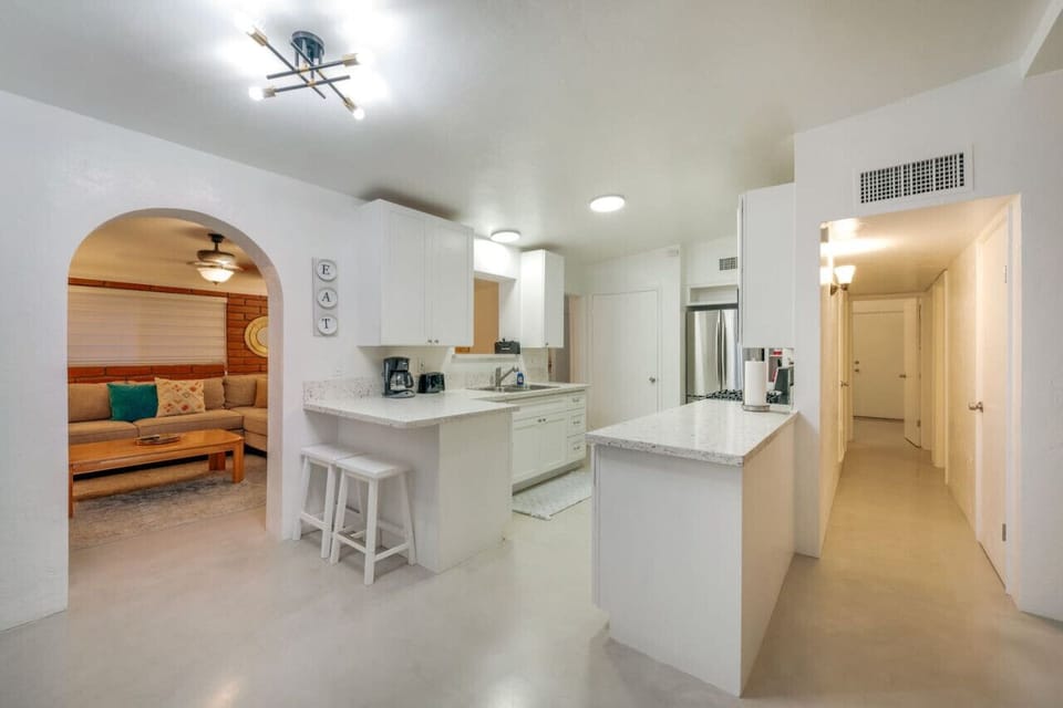 Newly polished concrete floors throughout the home and kitchen area lead into the living space through a lovely arched doorway.