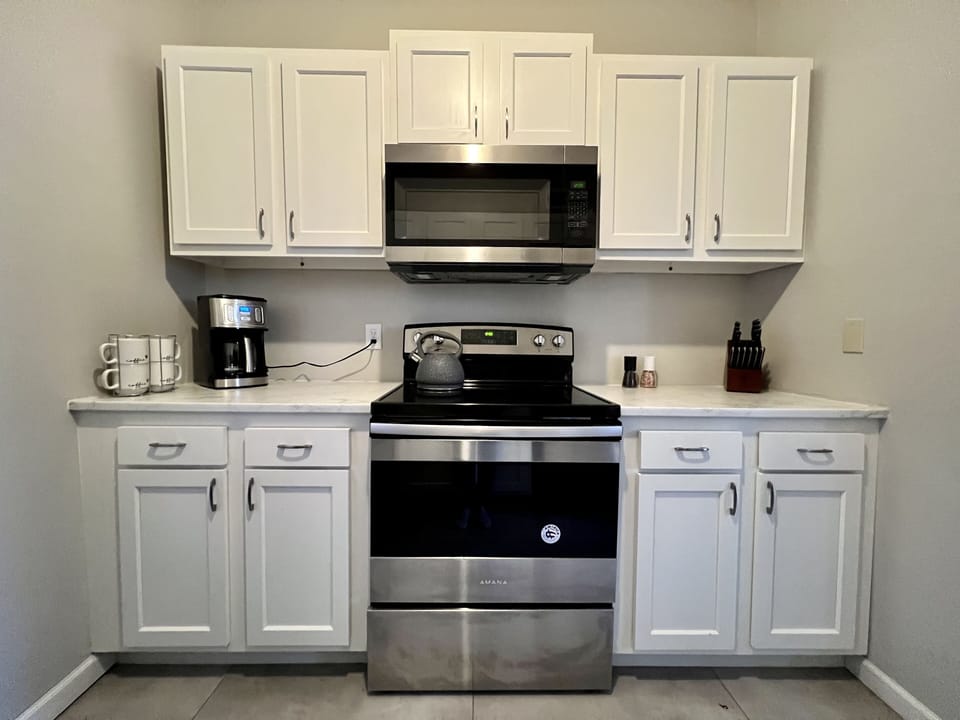 Electric stove with coffee maker and fully stocked kitchen for the avid cook.