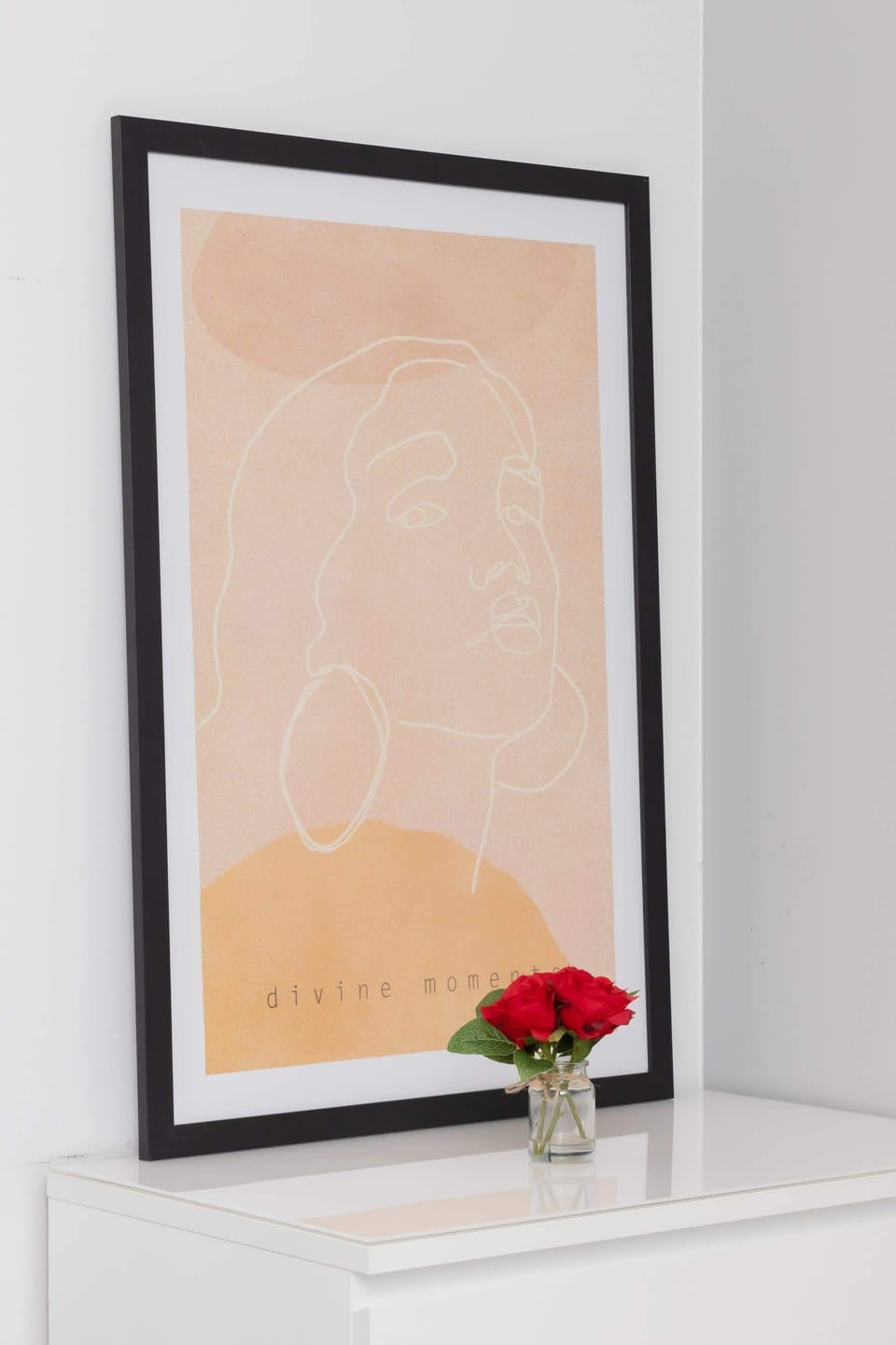 A simple yet elegant framed artwork with a small red rose on a dresser, adding personality to the interior.